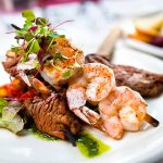 A elegantly presented plate of shrimp and beef skewers